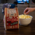 Person grabbing Snappy Movie Theater Butter microwave popcorn from a bowl
